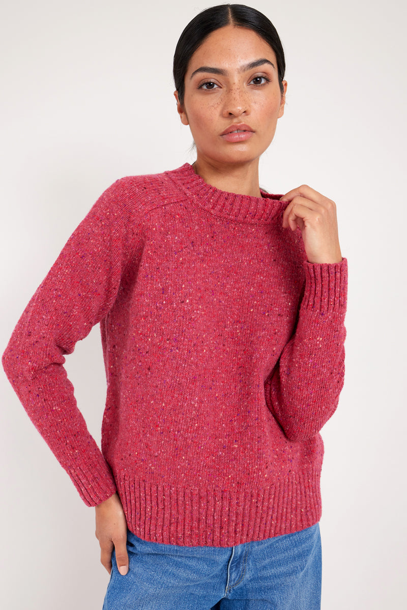 Model wears a raspberry colour merino wool jumper.