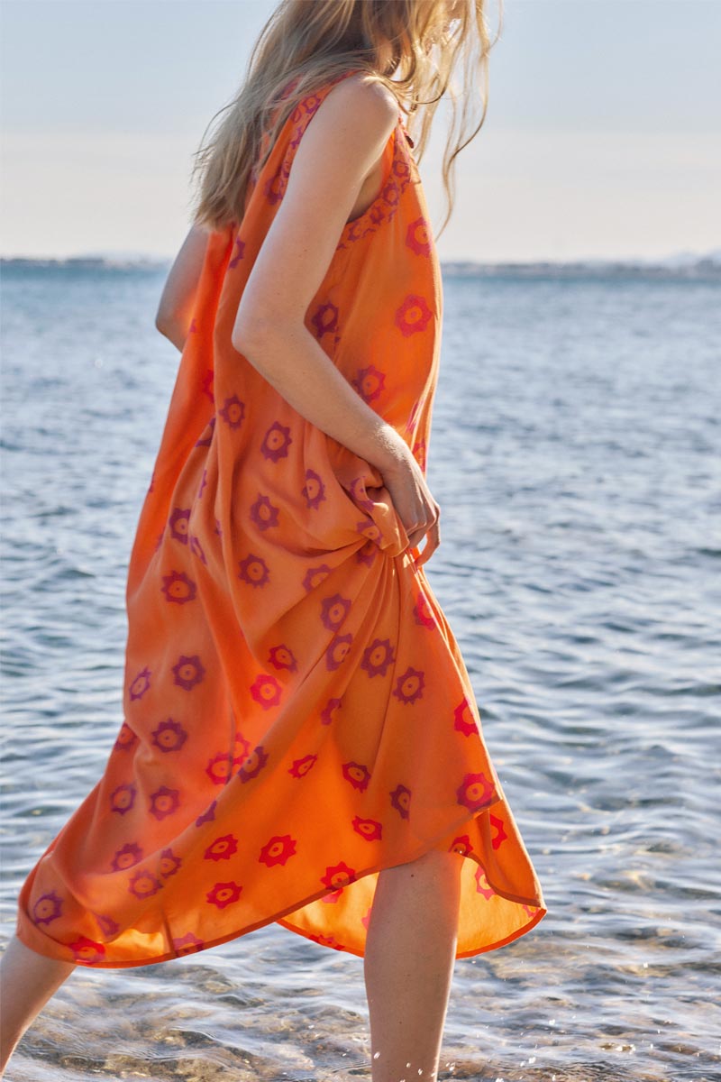 Side view of model paddling in the sea wearing East Nevaeh Sleeveless Dress