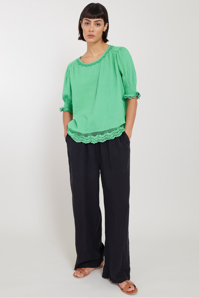 Model wears East Lena Green Cotton Blouse, hands in pockets