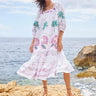 Model stands on rocks on the beach wearing East Heritage Zarella Embroidered White Dress