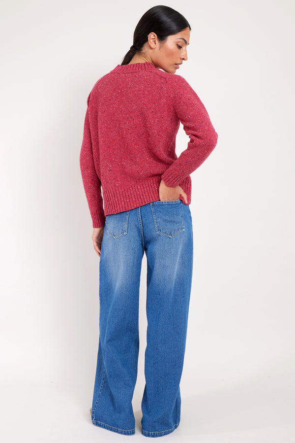 Model wears a raspberry colour merino wool jumper.